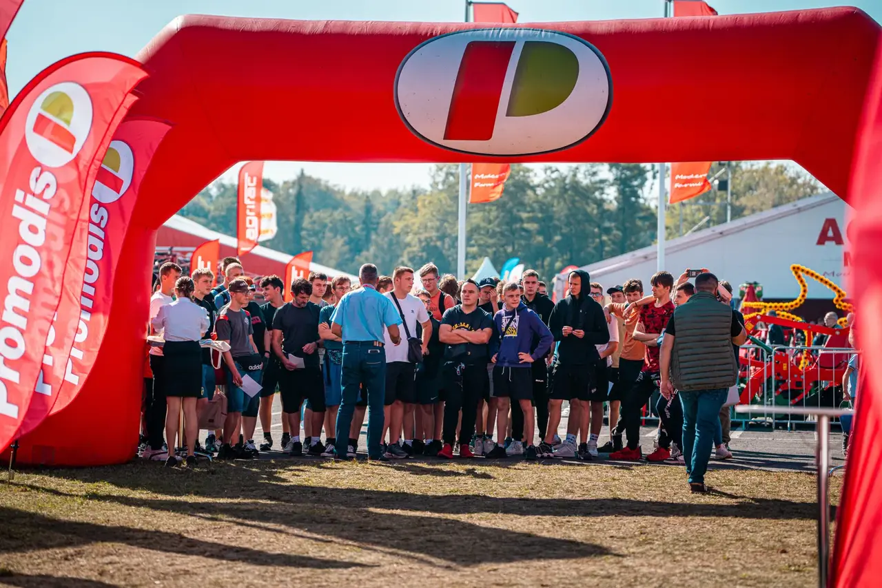 Grupa uczestników targów pod czerwoną bramą Promodis.