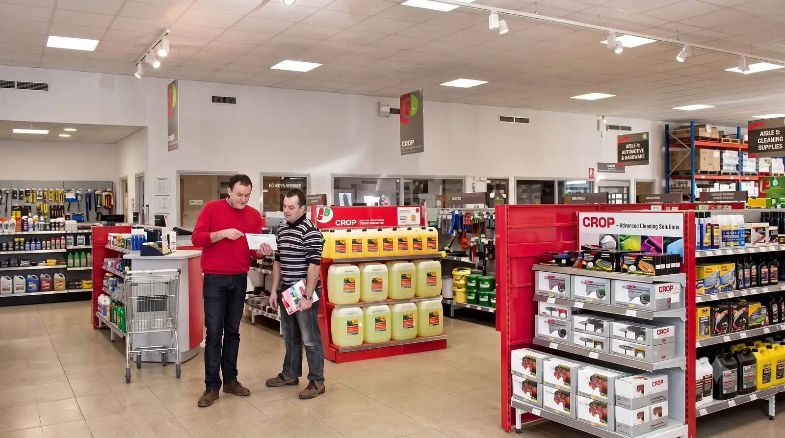 Wnętrze sklepu rolniczego Promodis z regałami wypełnionymi częściami i płynami eksploatacyjnymi.